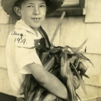 Leon A. Rushmore, Jr. carrying a bunch of corn at Rushmore Farms, Aug. 1919.jpg